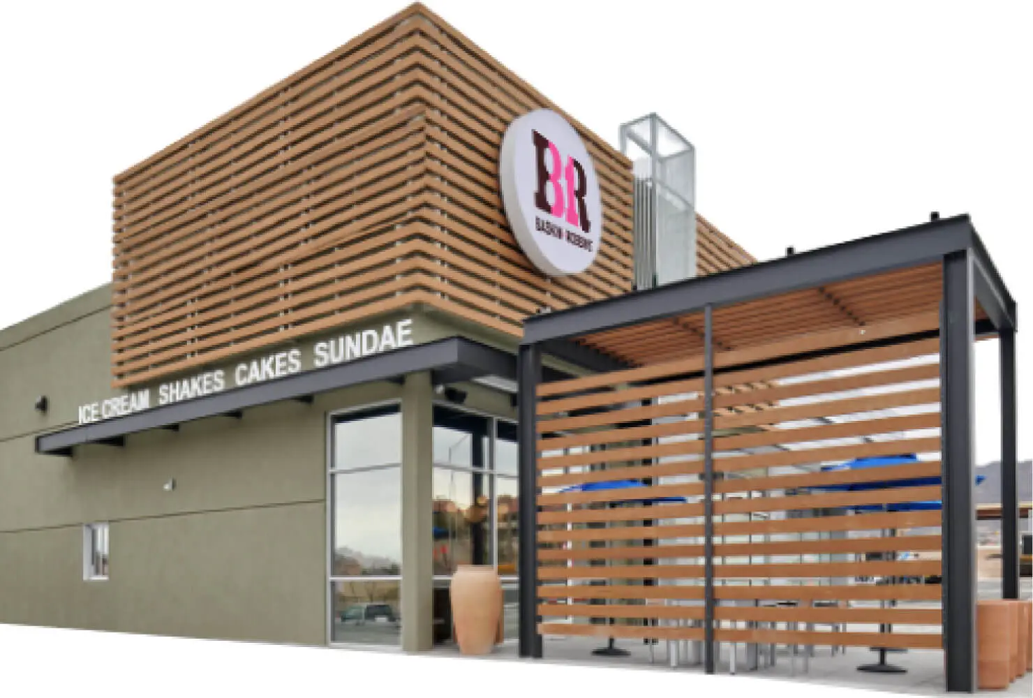 Exterior of a Baskin-Robbins ice cream shop with a wooden pergola and signs for ice cream, shakes, cakes, and sundaes.