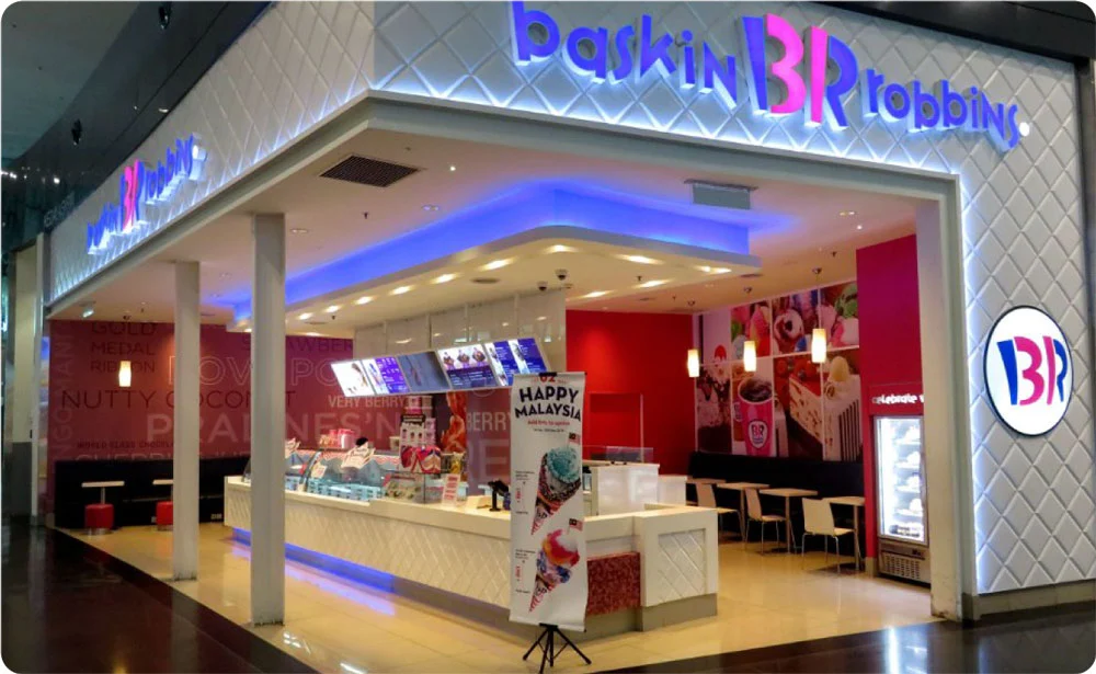 Exterior view of a Baskin Robbins ice cream shop with bright lighting and promotional signage.